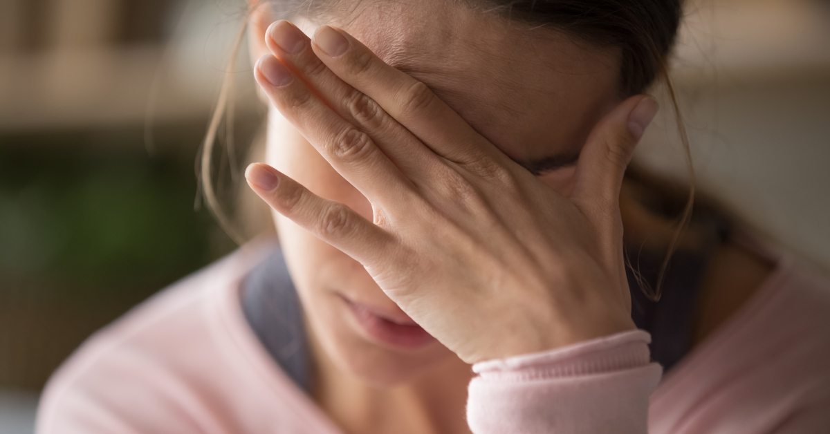 Donna che si copre la fronte con una mano per il dolore 