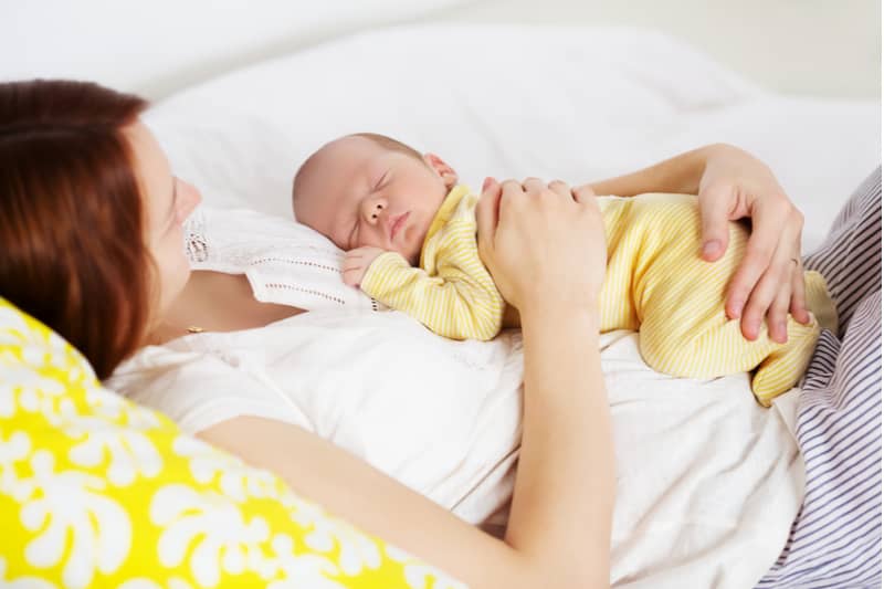 mamma in posizione semireclinata con il suo bambino steso sopra di lei a pancia in giù