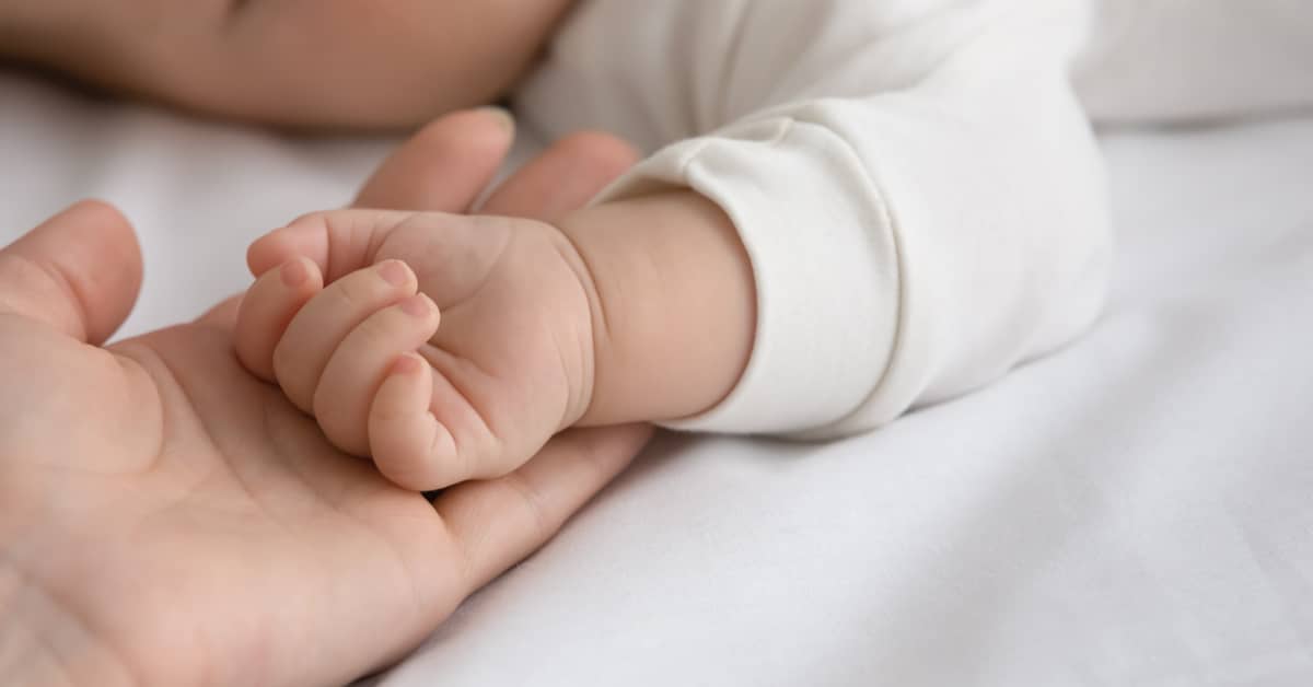 Mano di bimbo chiusa a pugno nella mano della mamma