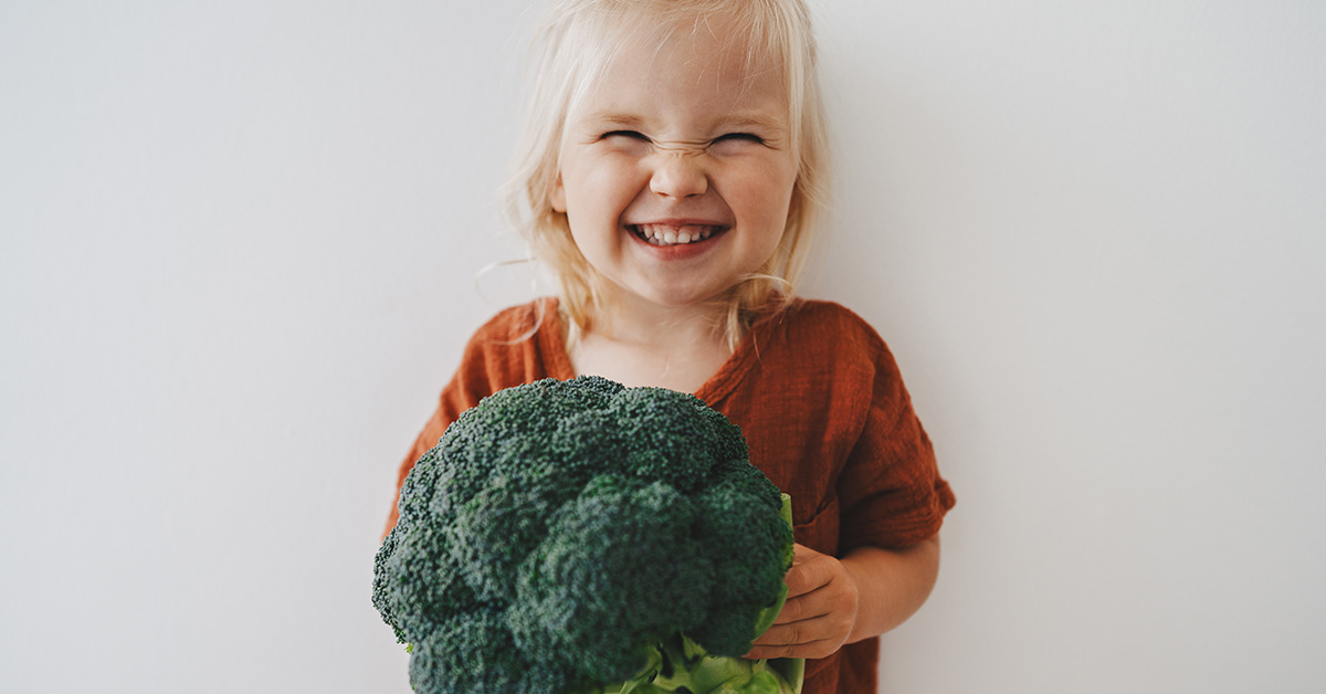 Bimba con un broccolo in mano