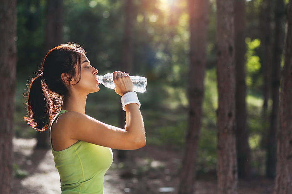 Donna che beve acqua nel bosco