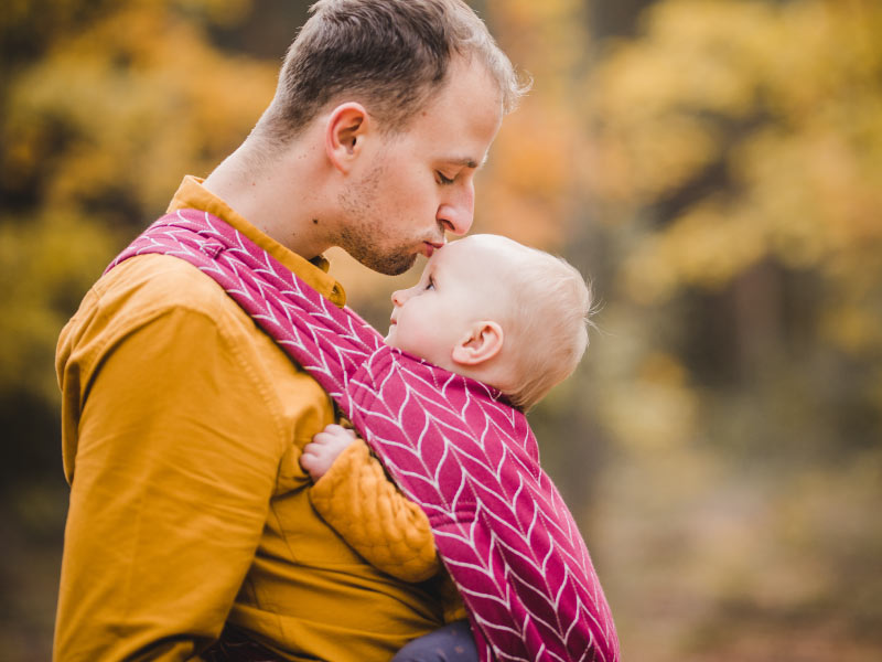 Bimbo tenuto in un marsupio dal papà