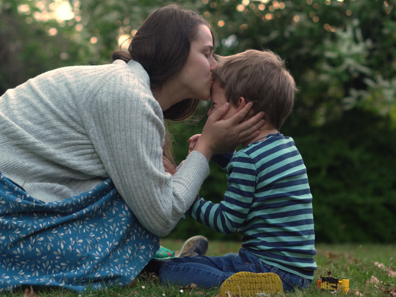 Mamma che accarezza e bacia un bambino in lacrime