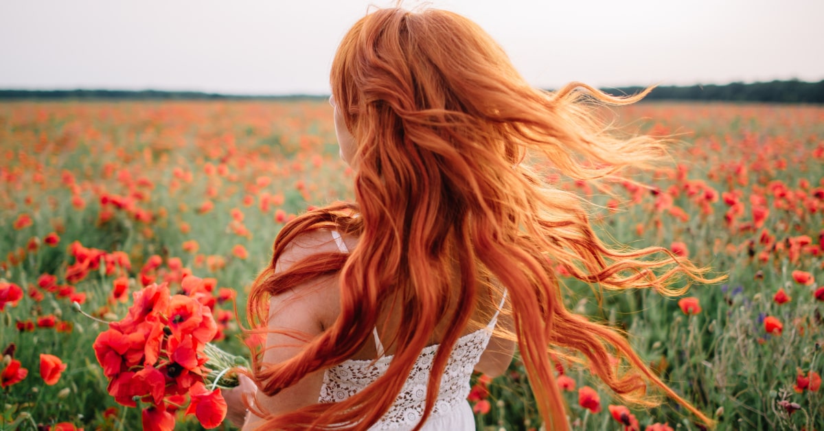 Donna dai capelli rossi in un campo di papaveri, concetto di libertà