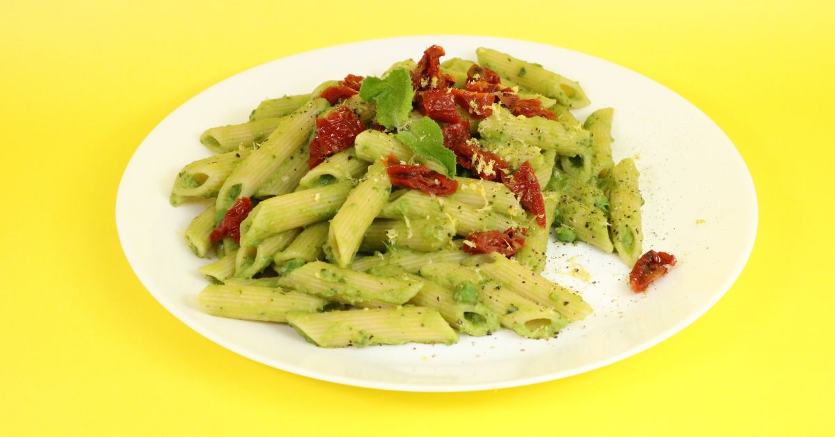 Piatto di penne con piselli pomodorini secchi e lievito alimentare