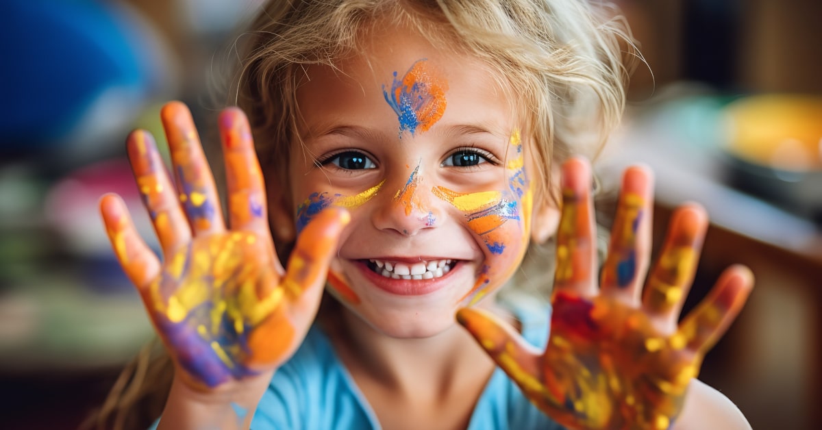 Bambina felice che mostra le mani sporche di colore dopo sessione di arteterapia