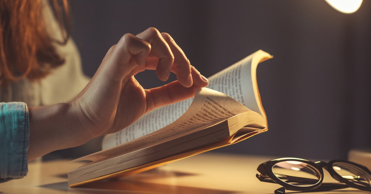Donna che gira la pagina di un libro