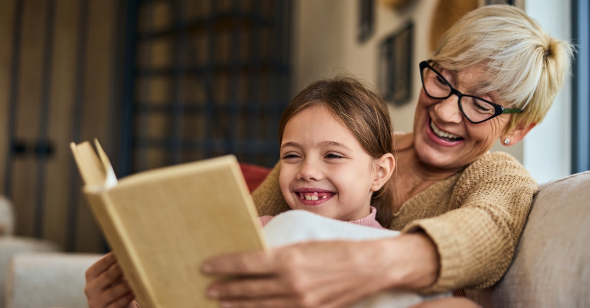 Nonna che legge un libro alla nipotina, benefici della lettura a voce alta
