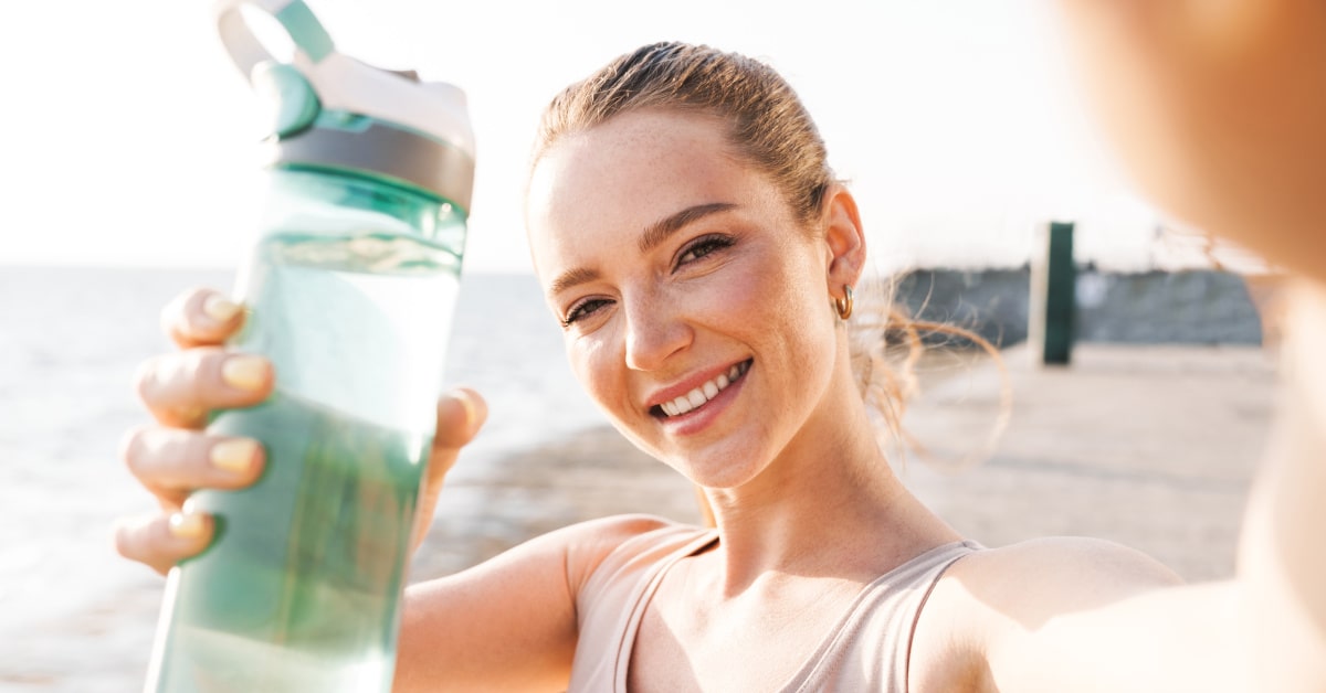 Donna all'aperto con borraccia di plastica e acqua