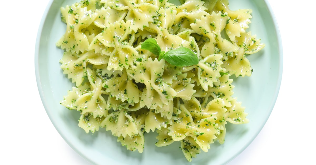 Piatto di farfalle con pesto di zucchine, pomodorini e semi di girasoli e foglie di basilico