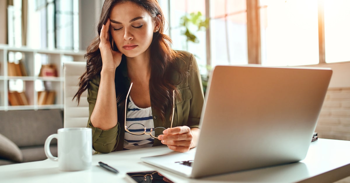 Donna alla scrivania mentre lavora stressata e affaticata