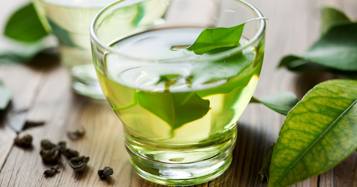 Tazza di tè verde con foglie sparse