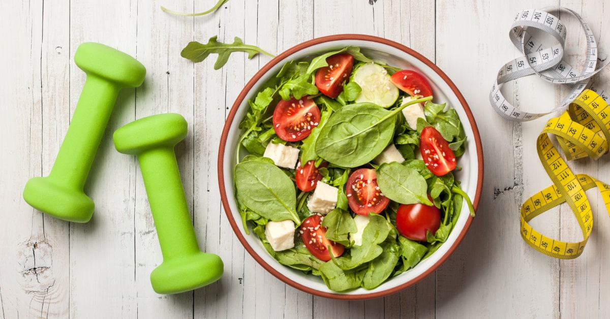 Piatto di verdura fresca con pesi e metro, concetto di benessere e vita equilibrata