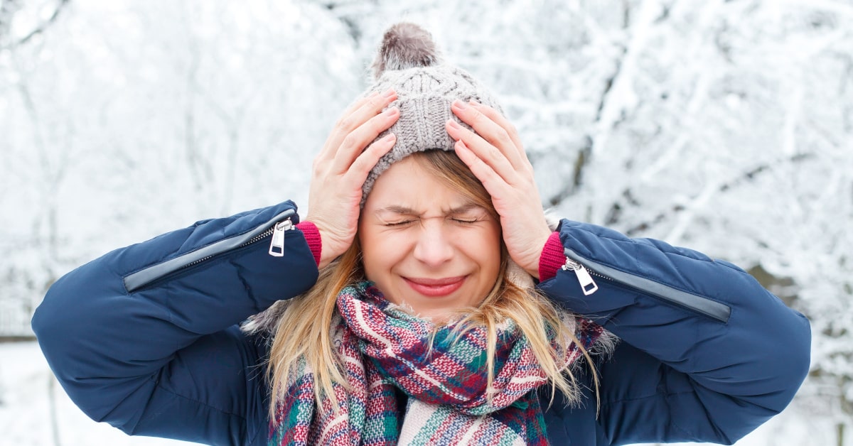 Donna all'aperto in una giornata con la neve e mal di testa