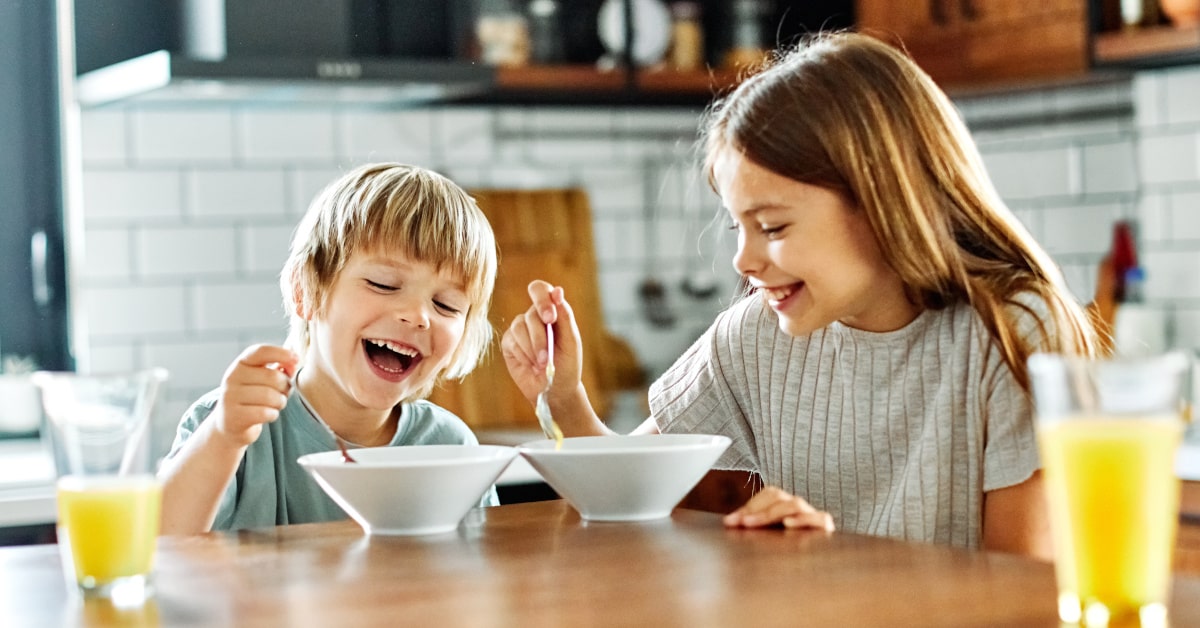 Fratello e sorella che fanno una sana colazione con cereali e succo di frutta