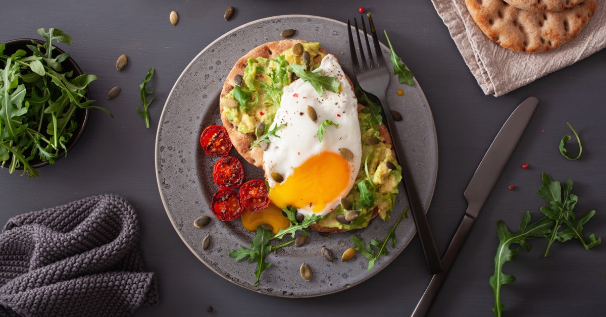 Piatto di toast con avocado, uova e rucola 