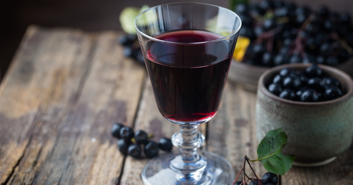 Succo di Aronia in calice di cristallo con bacche sul tavolo