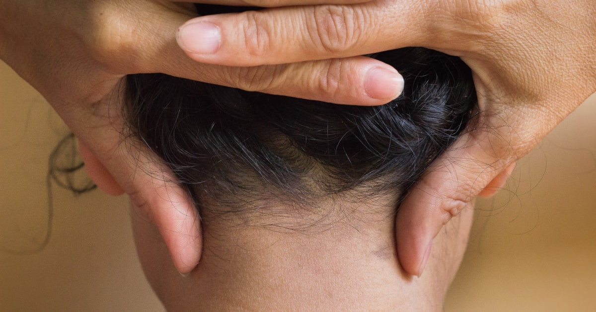Donna che massaggia con le dita delle mani il punto di agopuntura GB20, alla base della nuca