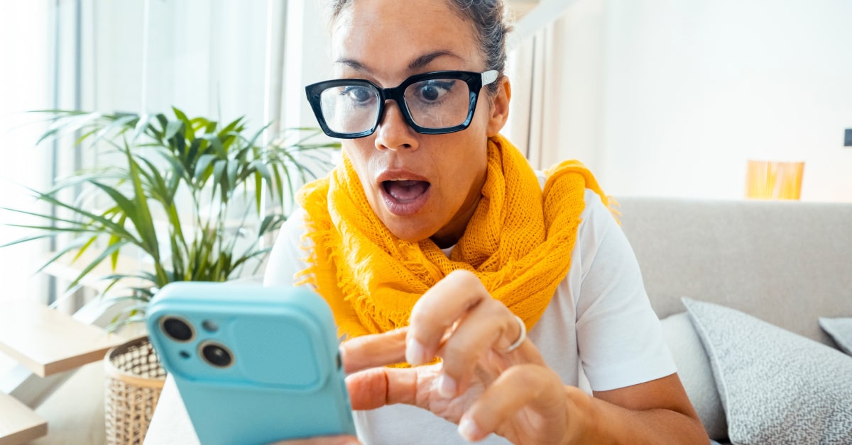 Donna che guarda nel cellulare fra stupore e ansia
