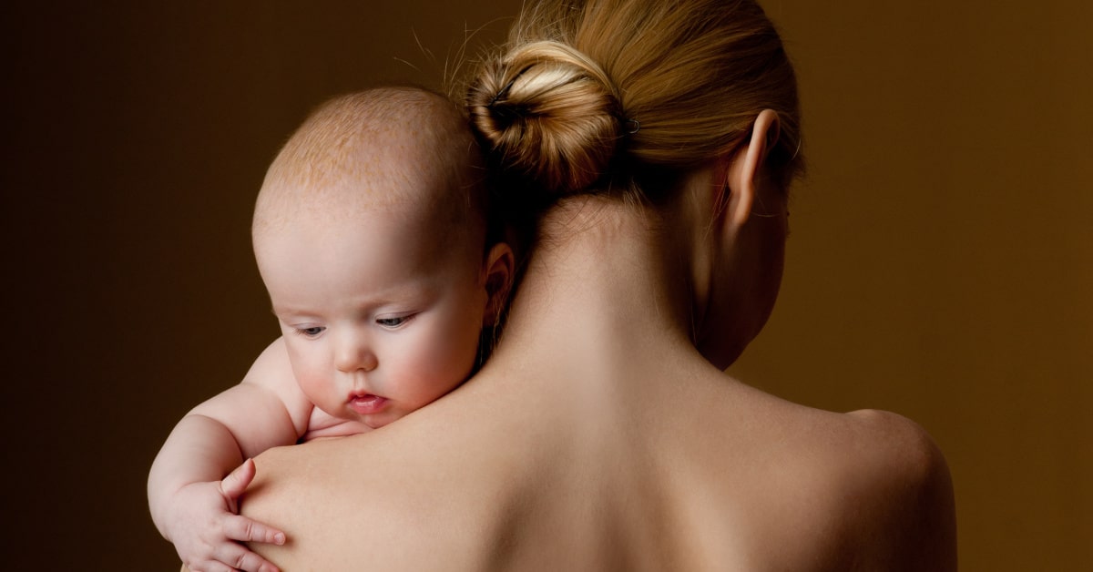 Neonato in braccio alla mamma di schiena, contatto pelle a pelle