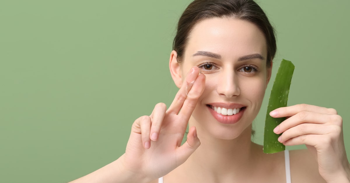 Donna che tiene in mano una foglia di aloe vera e mostra il gel di aloe con due dita