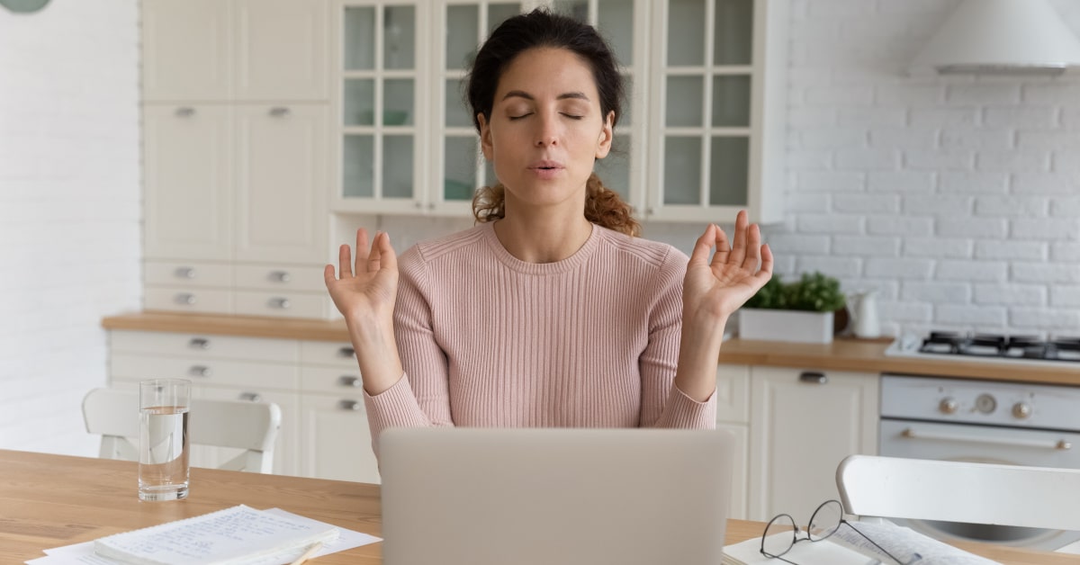 Donna che cerca di rilassarsi con respiri profondi davanti al computer