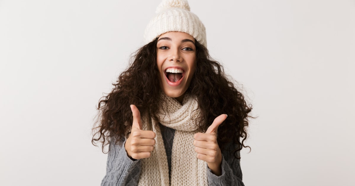Donna vestita da inverno con i pollici alzati