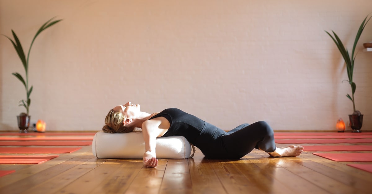 Donna che fa yoga con un cuscino sotto la schiena