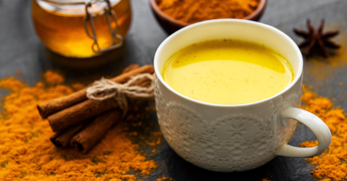 Tazza di golden milk con cannella, curcuma e miele sul tavolo