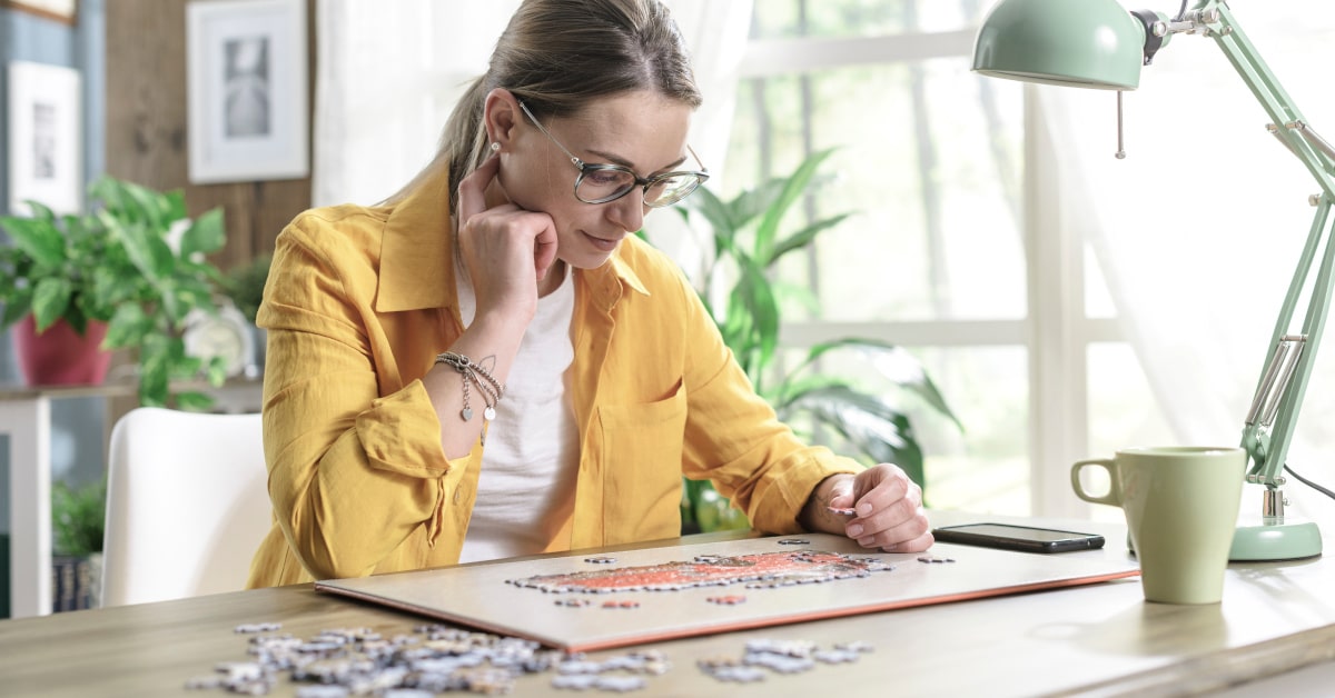 Donna seduta alla scrivania mentre si rilassa facendo un puzzle