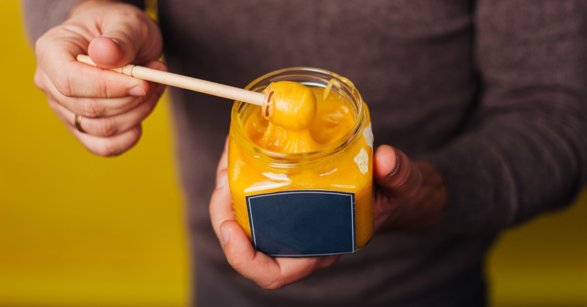 Donna che tiene in mano un vasetto con pasta di curcumam per golden milk