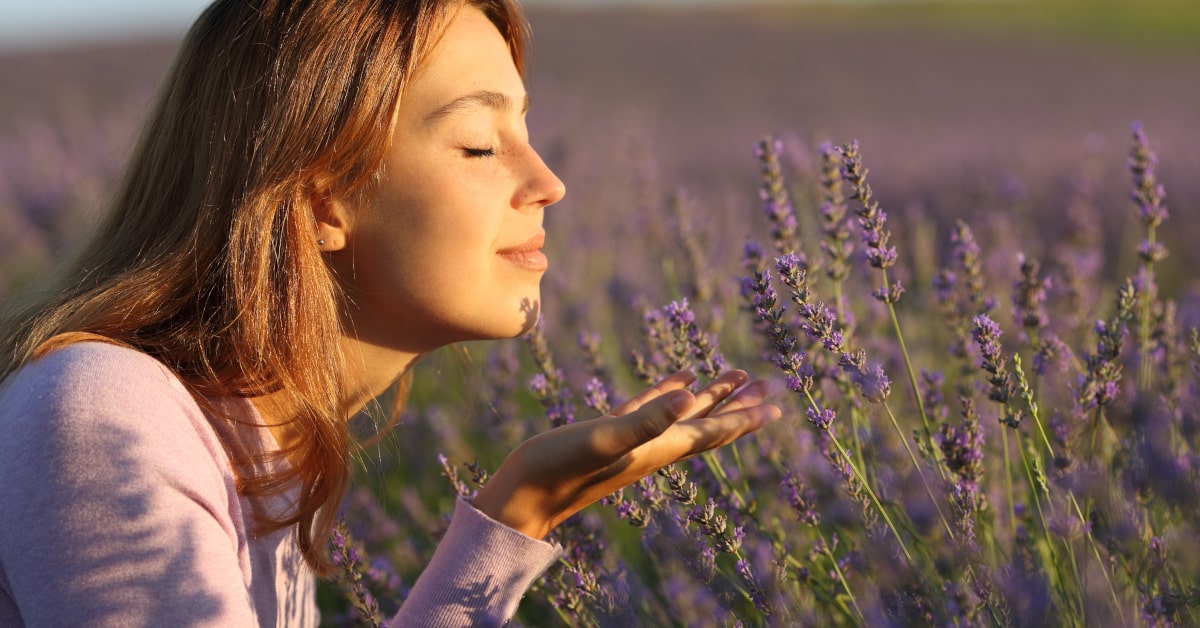 Donna che annusa i fiori di lavanda in un campo in estate