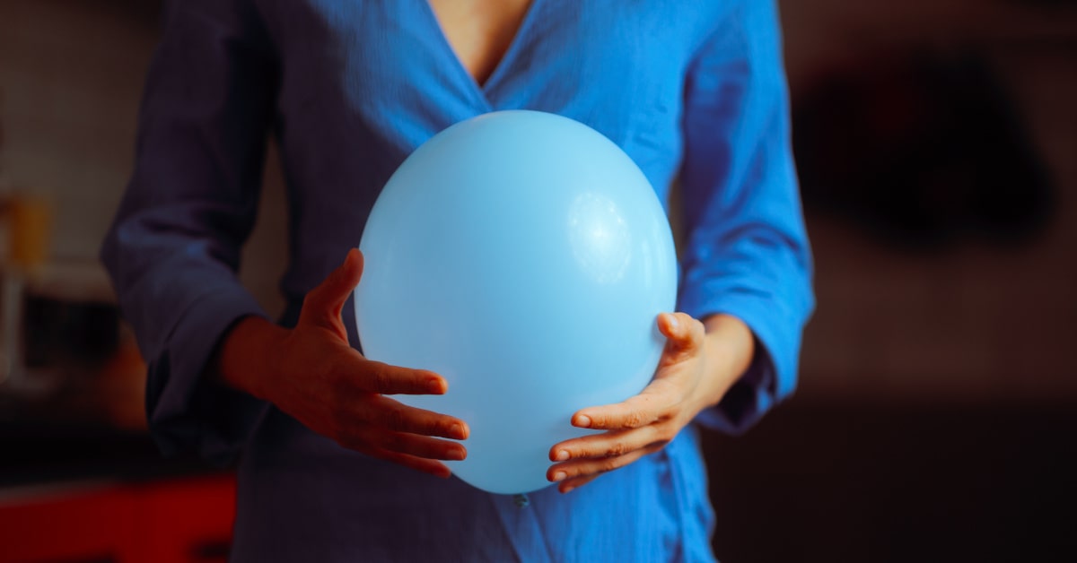 Donna che tiene in mano un palloncino all'altezza della pancia