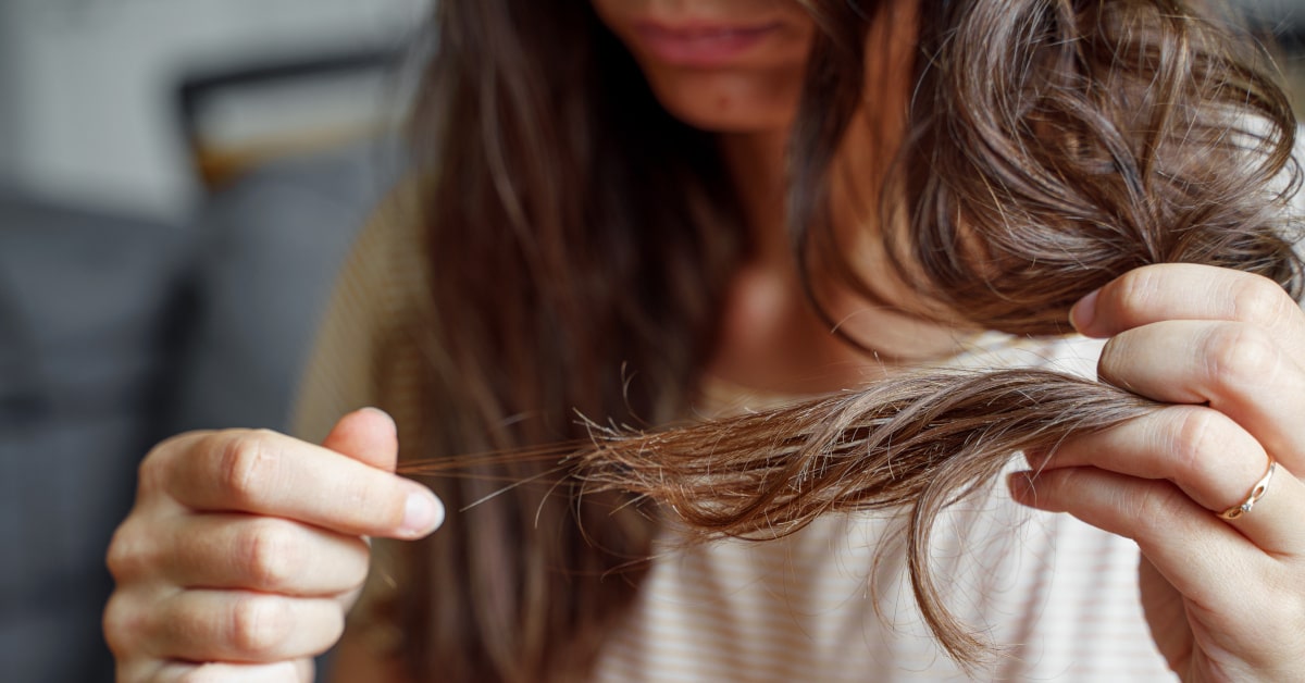 Donna con ciocca di capelli in mano, con perdita di capelli