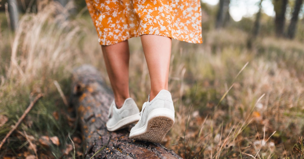 Donna che cammina in natura su un tronco di albero caduto a terra