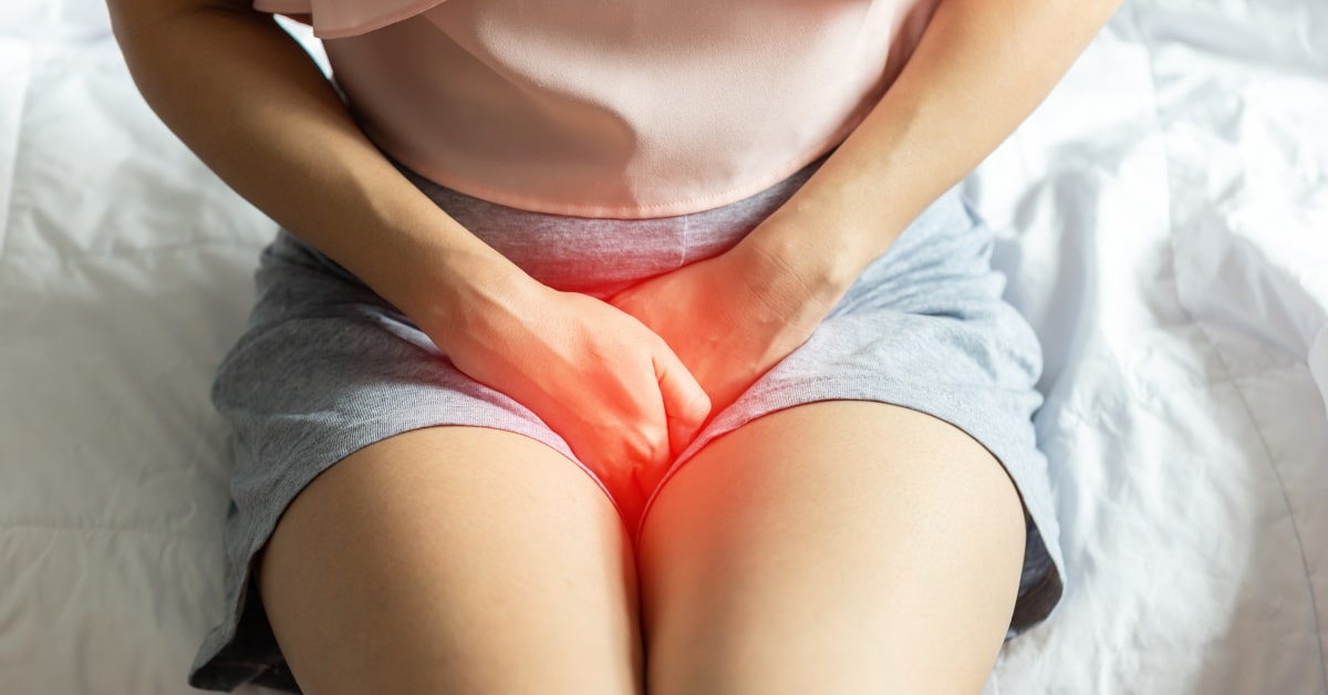 Donna seduta sul letto con infiammazione e cistite 