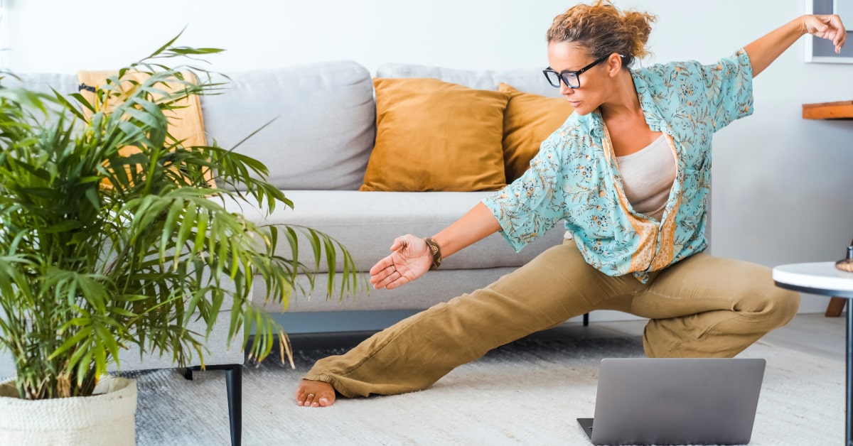 Donna in casa che esegue esercizi di tai chi