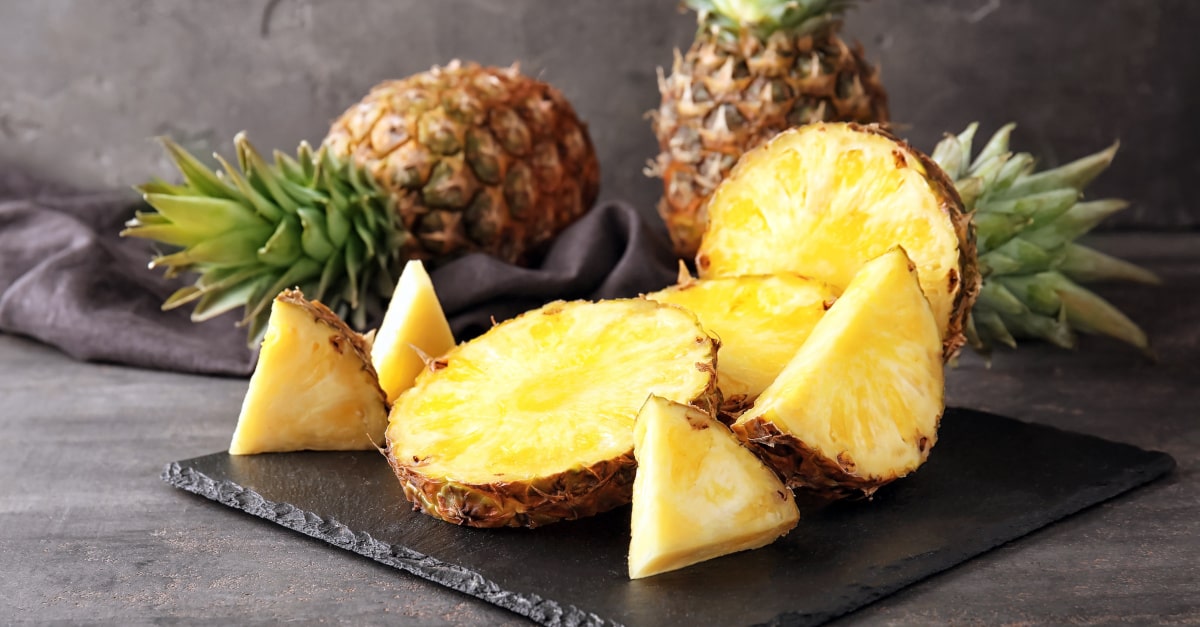 Ananas intere e a fette su un tagliere 