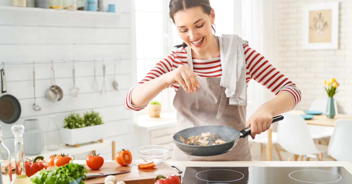 Donna mentre prepara il pranzo ai fornelli in cucina