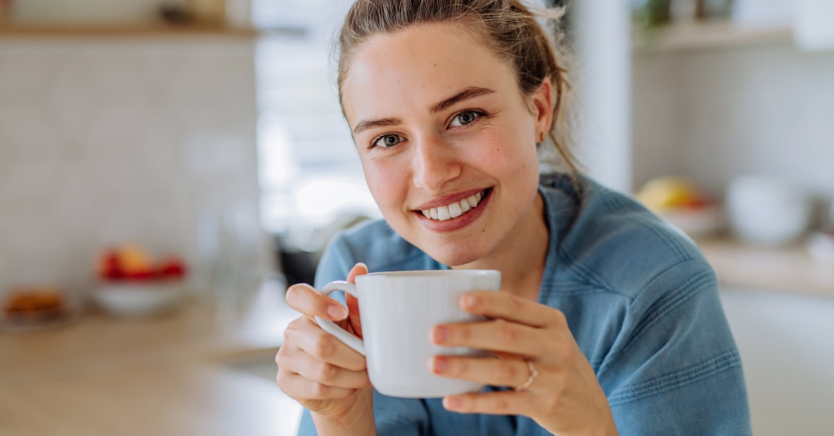 Donna sorridente con tazza per caffè in mano