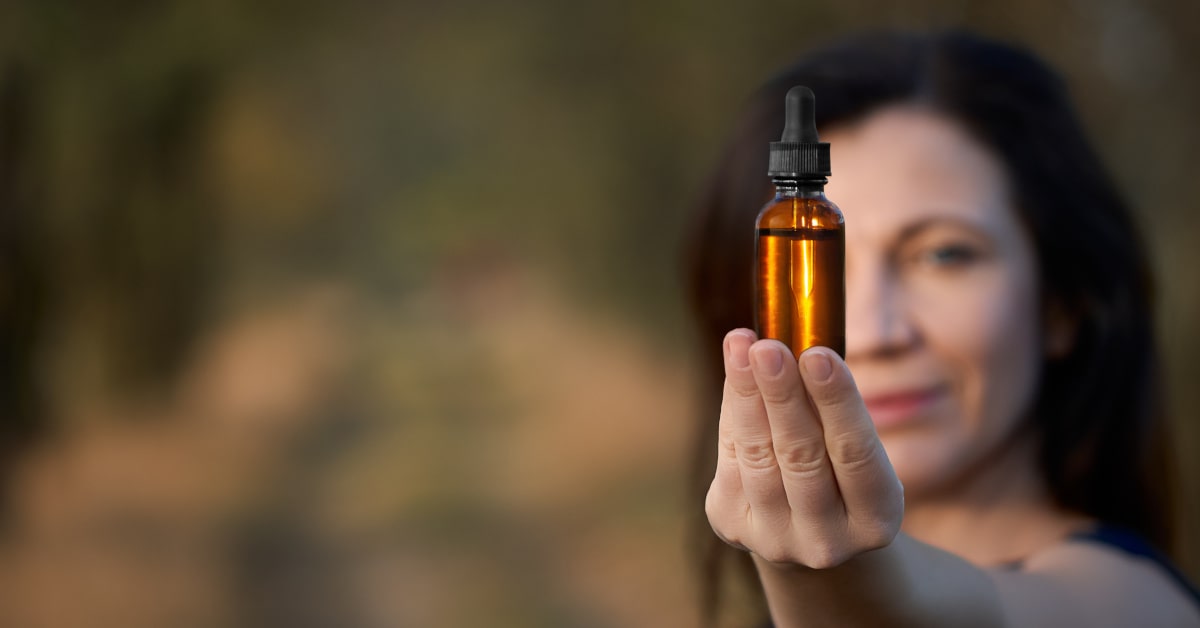 Donna che tiene in mano una boccetta di vetro scuro con miscela di fiori di Bach