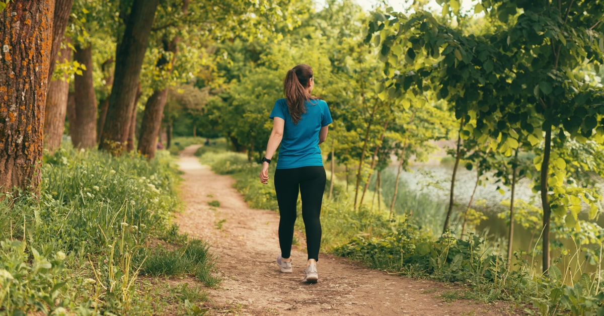Donna che cammina in un sentiero in mezzo alla natura in estate