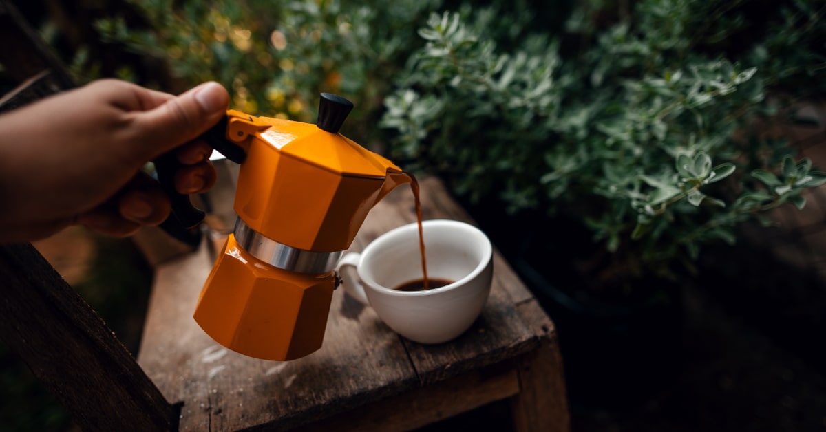 Donna che versa il caffè da una moka arancione 