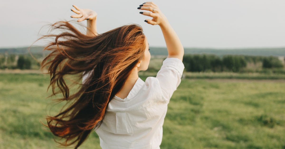 Donna di spalle all'aperto con i capelli lunghi al vento