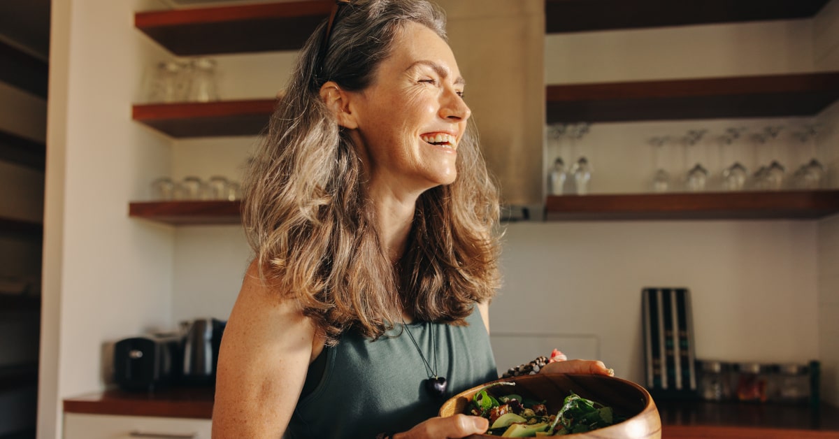 Donna sorridente con una ciotola di insalata e avocado 