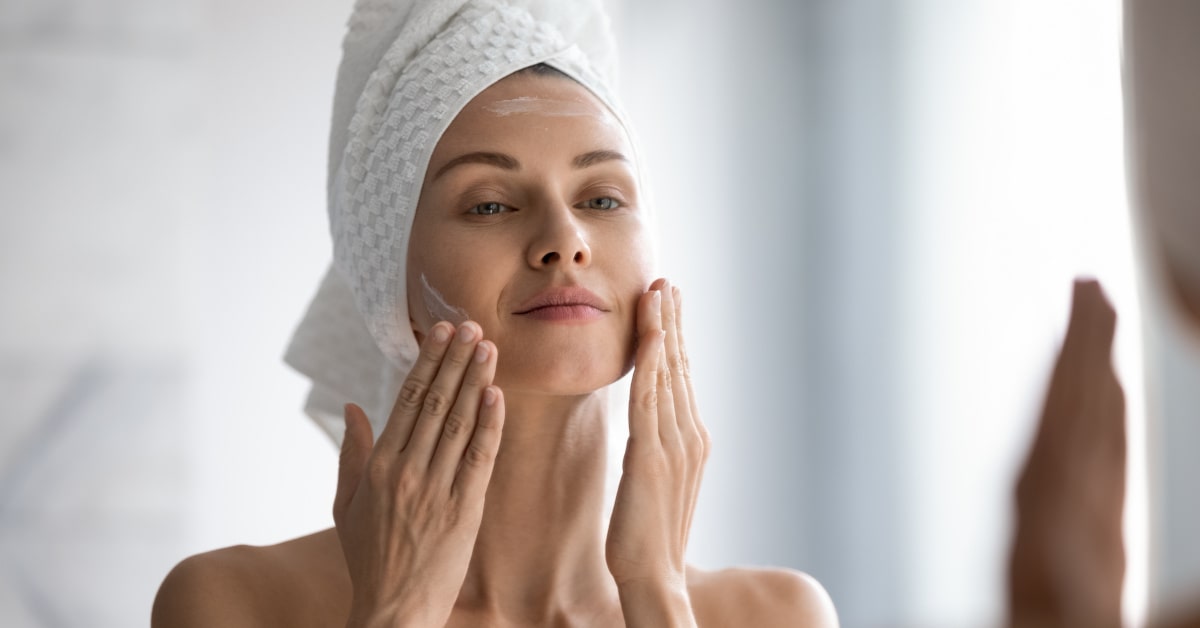 Donna che si spalma una crema in viso