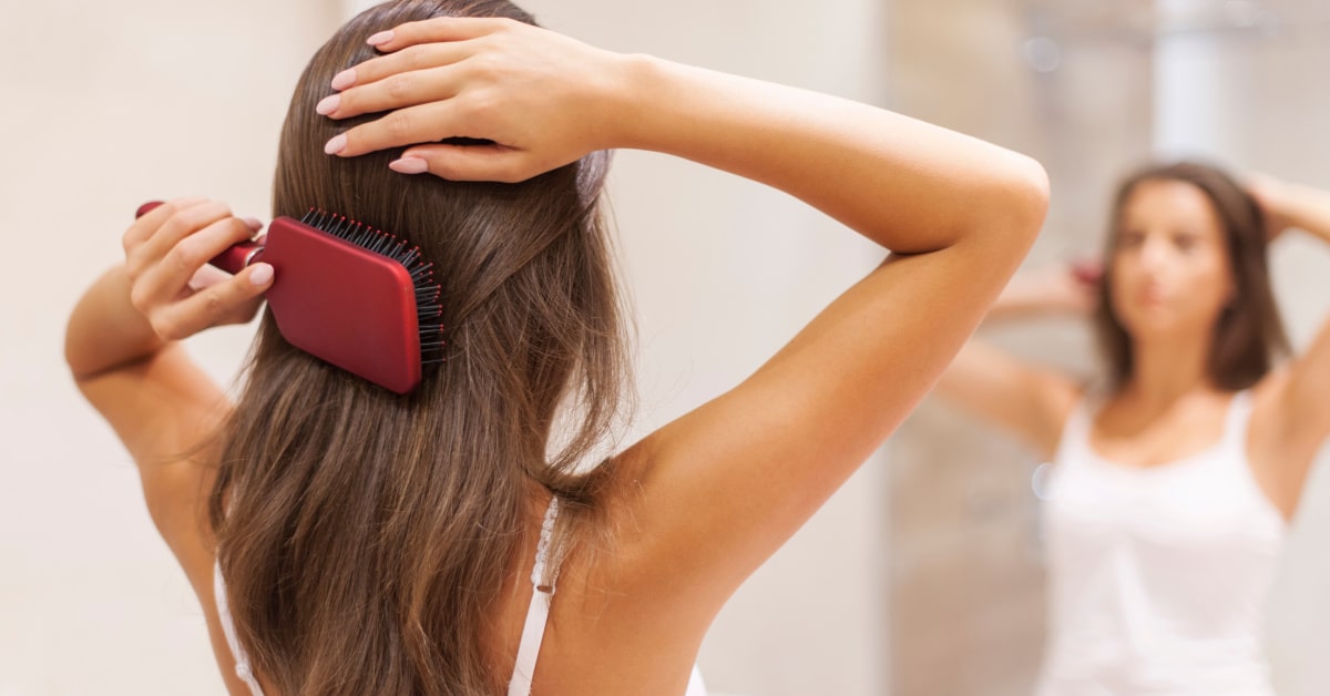 Donna che si spazzola i capelli davanti allo specchio