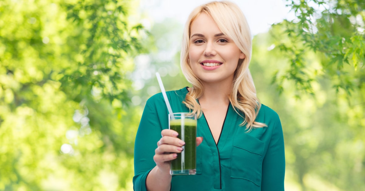 Donna all'aperto con in bicchiere di smoothie vegetale verde