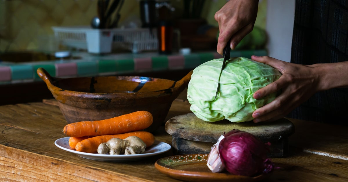 Uomo che taglia un cavolo per preparare le verdure fermentate