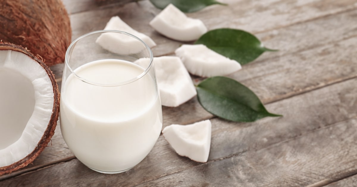 Bicchiere con latte di cocco e pezzi di noce di cocco matura